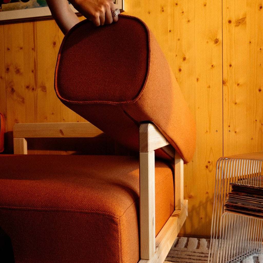 Stay sohva, lähikuva siitä, kuinka tyyny nostetaan helposti pois käsinojan päältä, kangas Vintage Orange.
