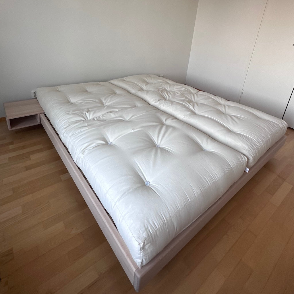 Kaksi luonnonvalkoista futonpatjaa. Kuvassa myös käsittelemättömät Carre sänkyrunko ja Carre yöpöytä.