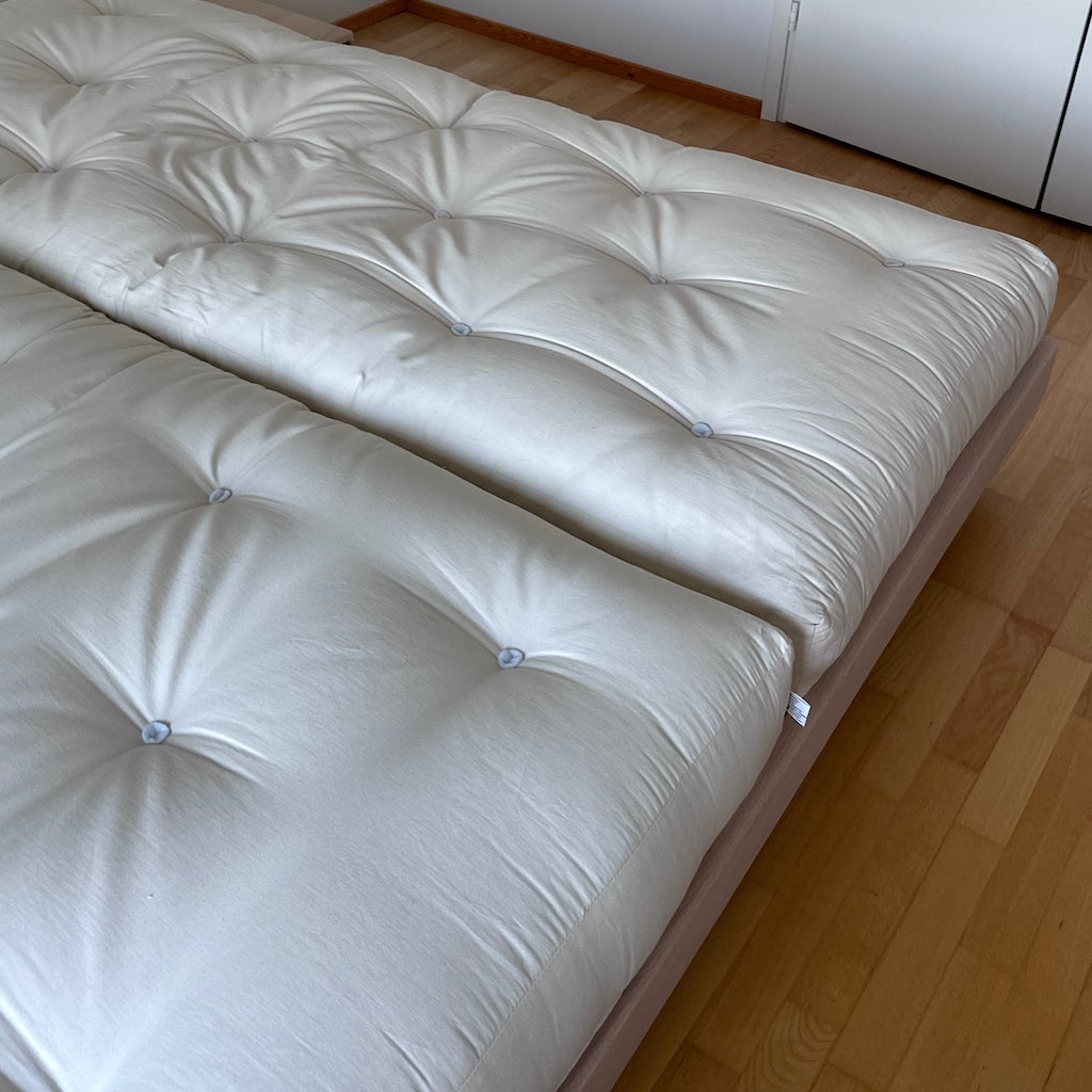 Kaksi luonnonvalkoista futonpatjaa. Kuvassa myös käsittelemätön Carre sänkyrunko.