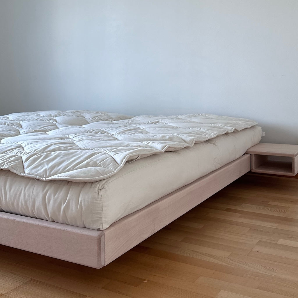 Kaksi luonnonvalkoista futonpatjaa. Kuvassa myös kapeat Villana villapetauspatjat sekä Carre sänkyrunko ja Carre yöpöytä.